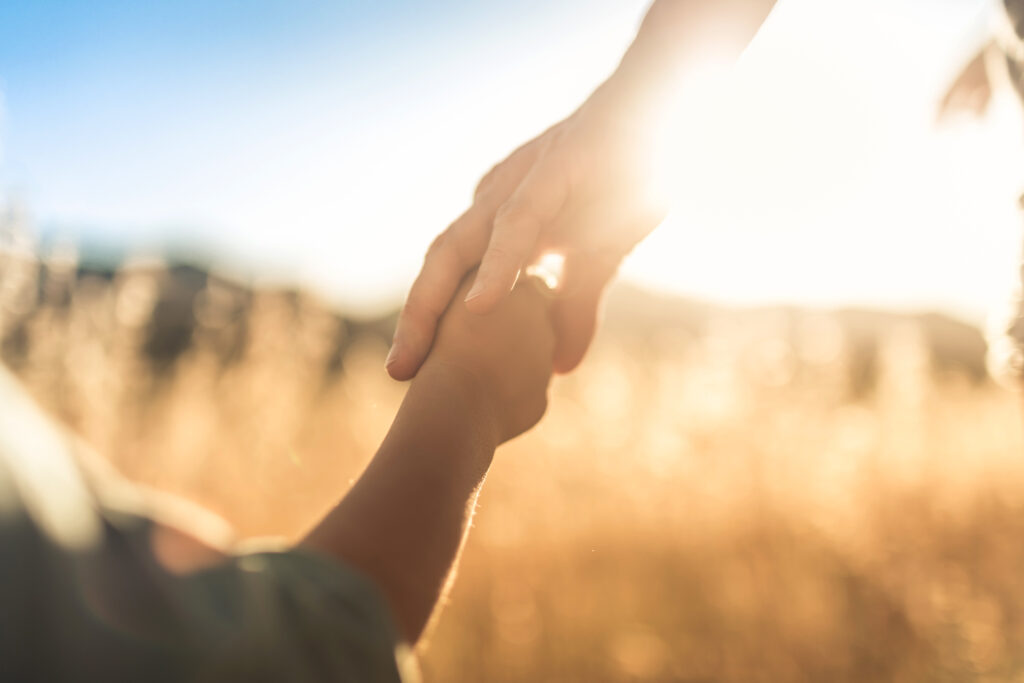 Woman and child holding hands in field